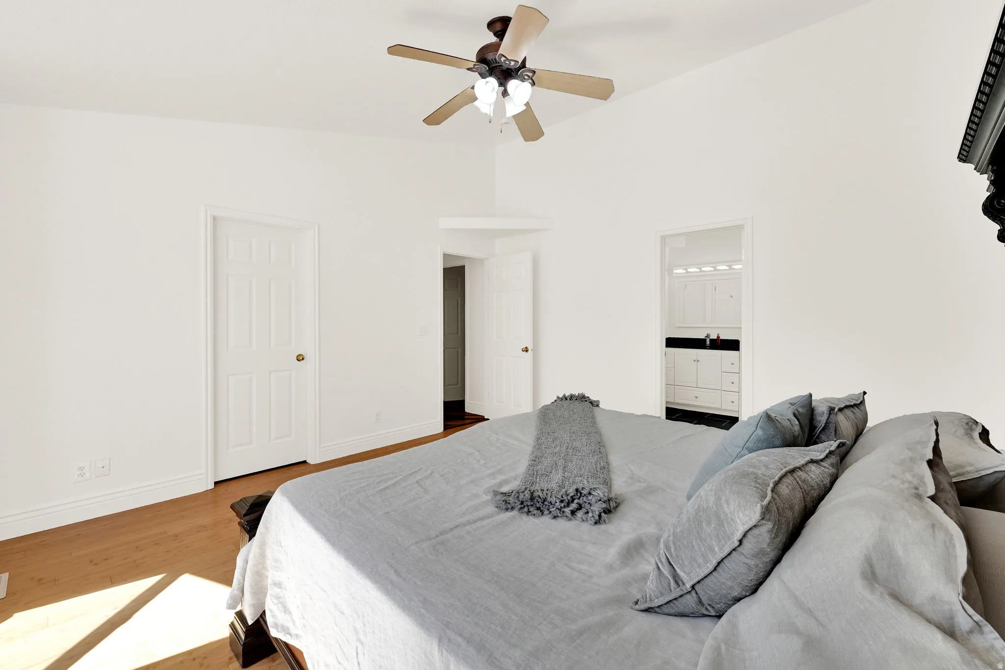 Bright interior space featuring wood-finish flooring, a ceiling fan with light fixture, and white painted walls