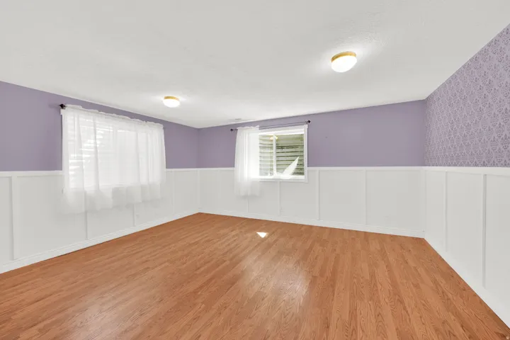 Wood-finish flooring throughout, complemented by white wainscoting and lavender-painted walls