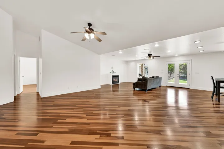 Spacious room with wood-finish flooring, white walls, and a vaulted ceiling
