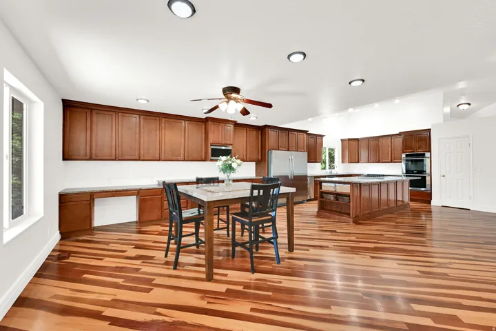Spacious kitchen featuring extensive wood cabinetry, stainless steel appliances, a large center island, and wood-finish flooring