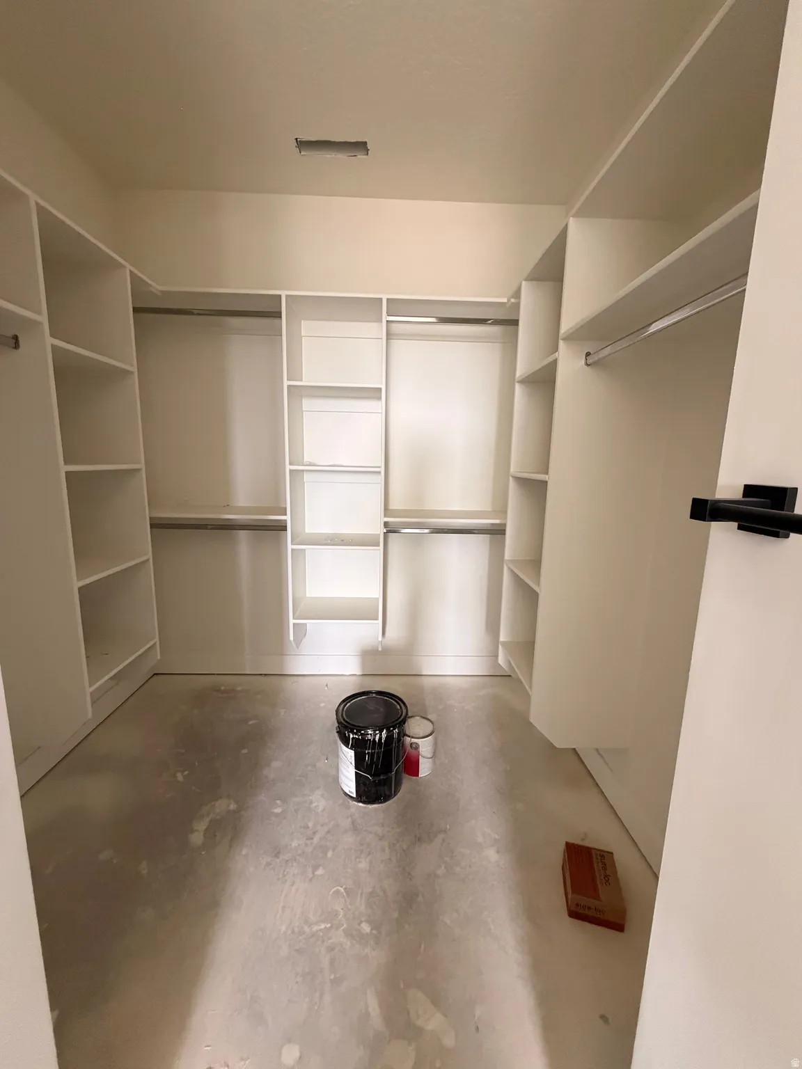 Expansive walk-in closet featuring white built-in shelving, multiple hanging rods, and a neutral wall color