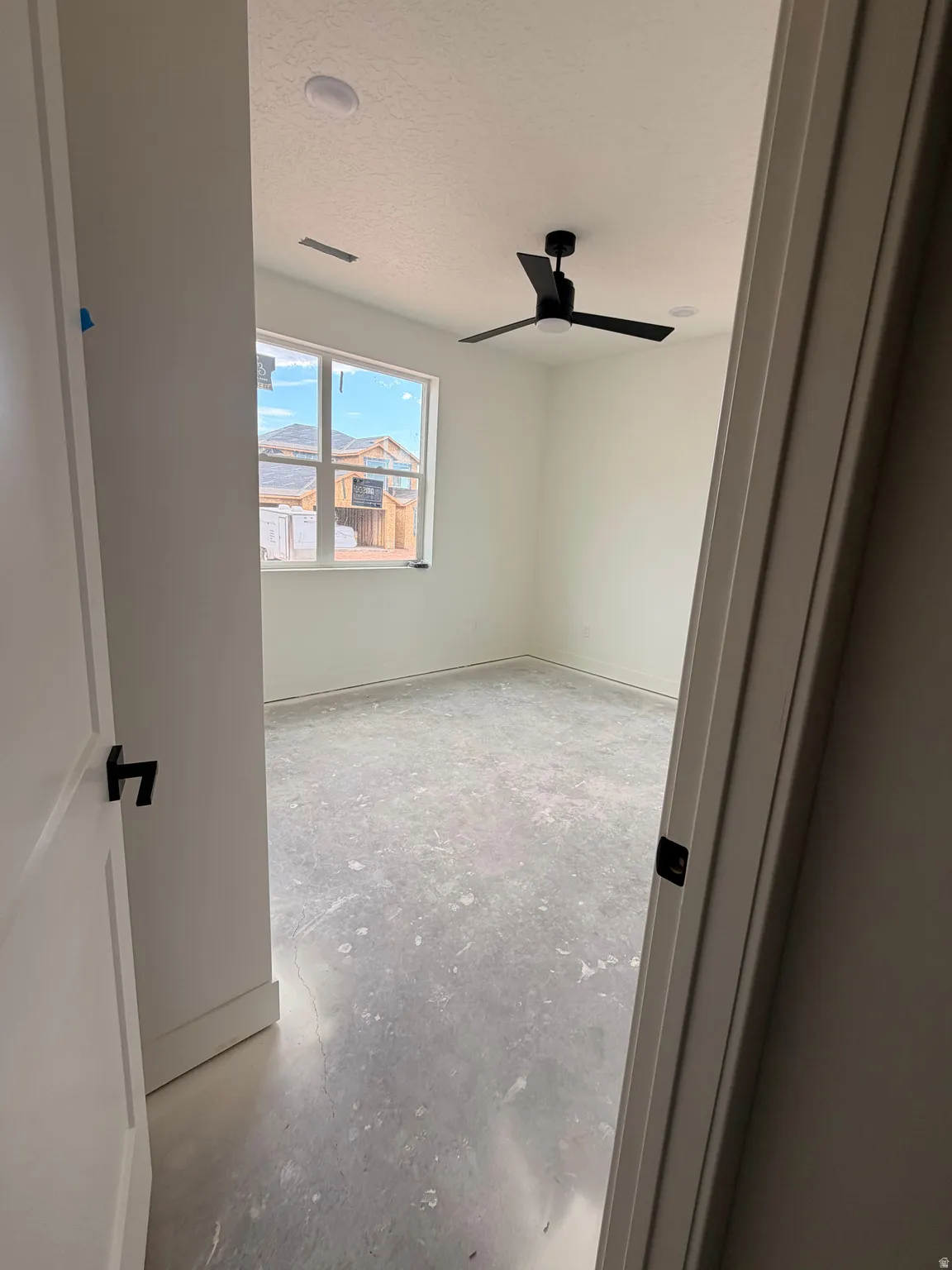 Room with a large window, a black ceiling fan, and recessed lighting