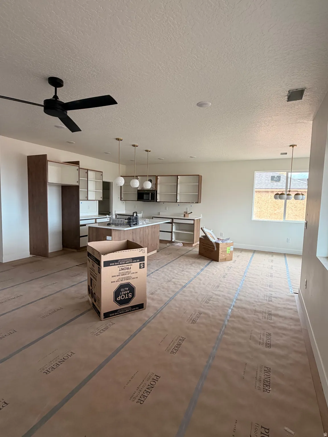 Open-concept kitchen and living area featuring contemporary pendant lighting, recessed ceiling lights, a modern ceiling fan, and ample natural light from multiple windows