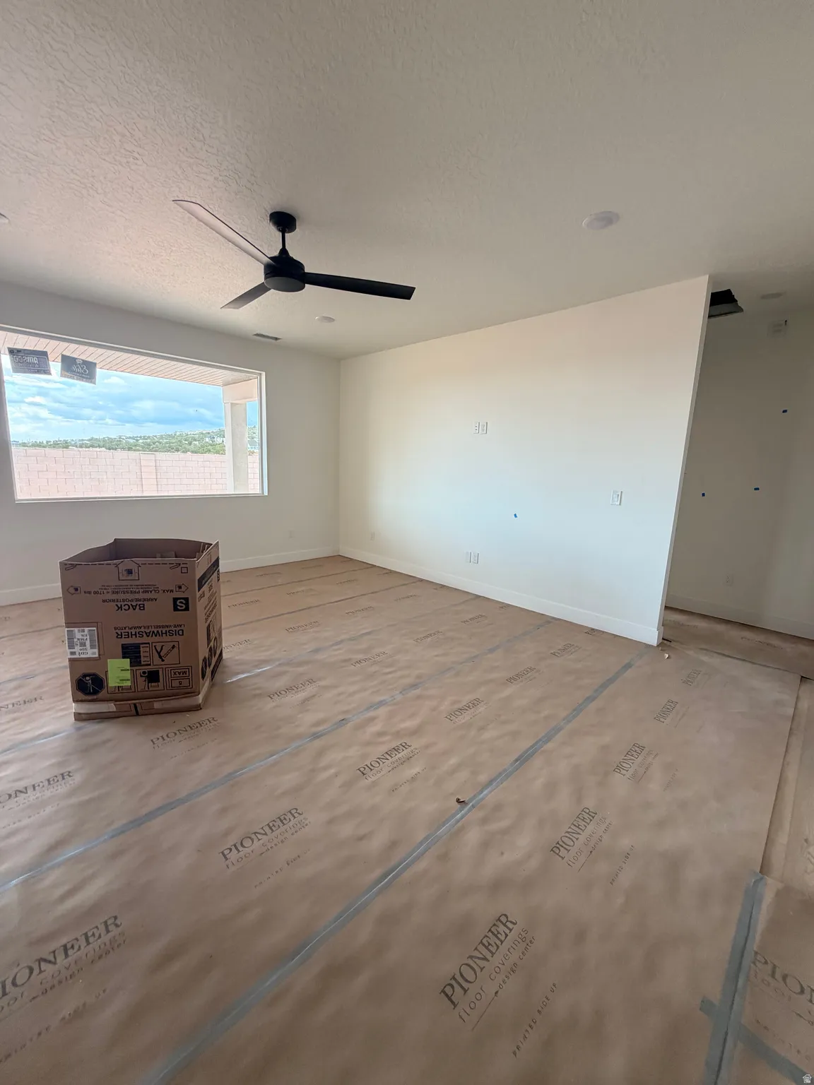 Spacious interior room featuring a modern black ceiling fan, recessed lighting, and a large horizontal window