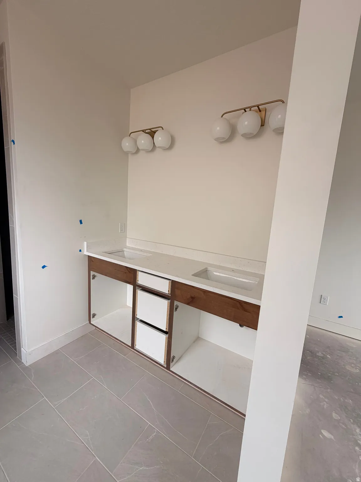 Dual vanity featuring integrated sinks, light-toned countertops, and wood-finish cabinetry