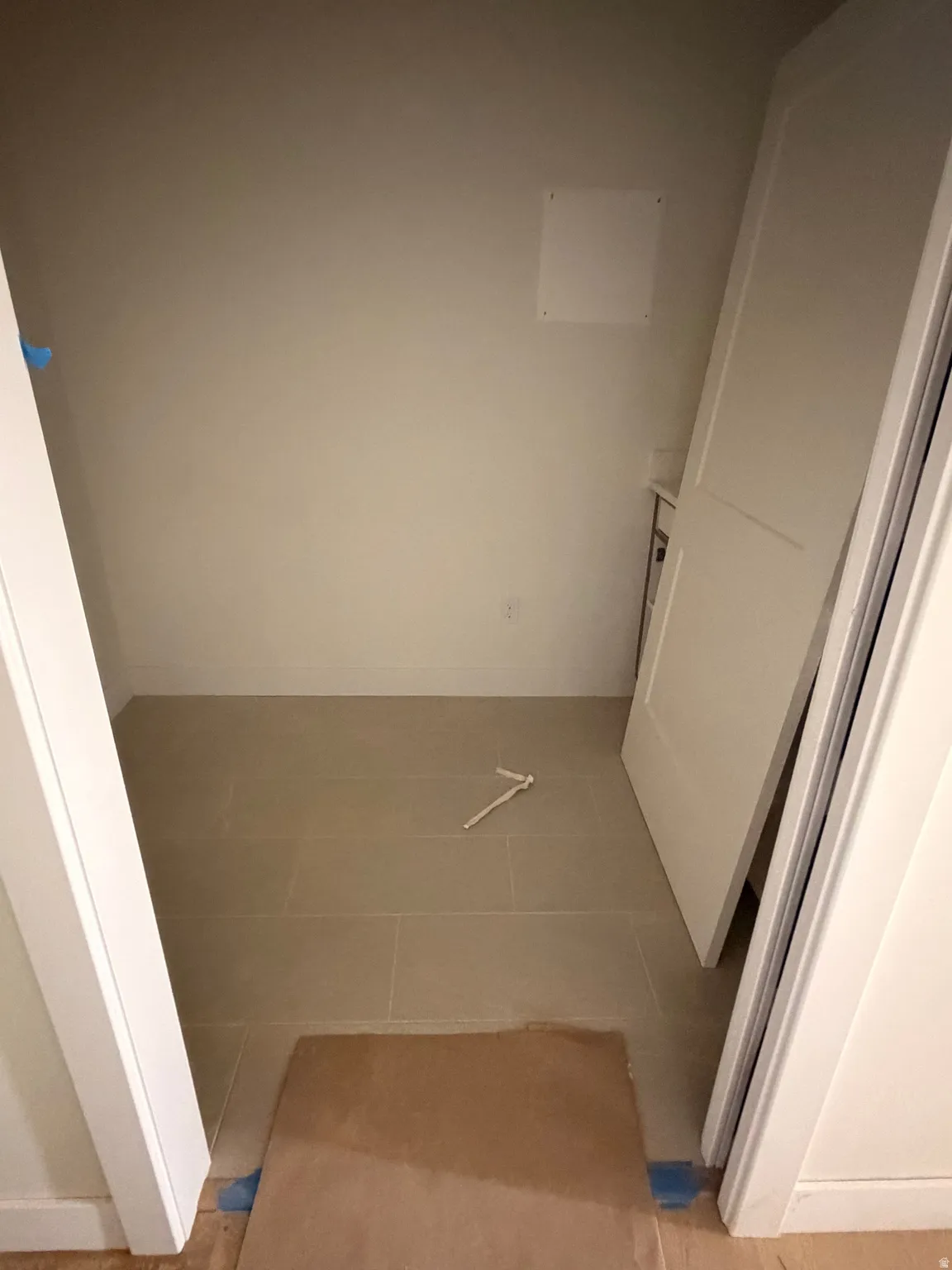Storage alcove featuring light-toned wall paint and light-colored rectangular floor tiles