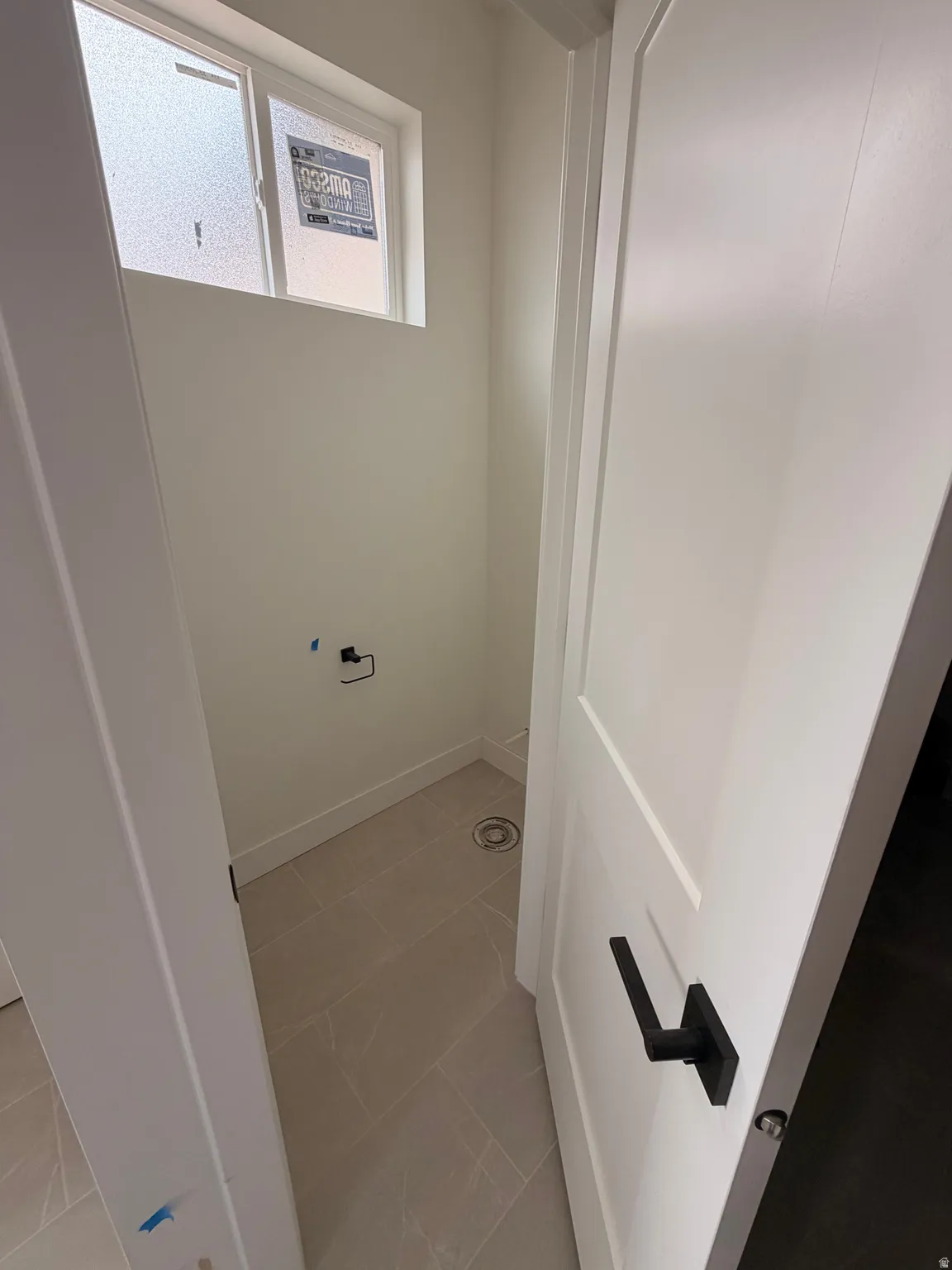 Compact utility space featuring neutral-toned tile flooring and a high-set window