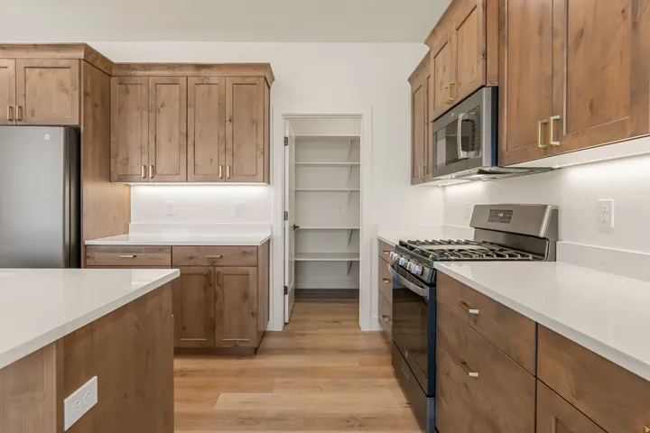 Modern kitchen featuring wood-finish cabinetry, light-toned countertops, and stainless steel appliances