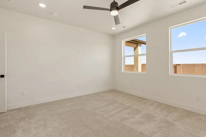 Spacious room featuring neutral carpeting, recessed ceiling lighting, and a modern ceiling fan