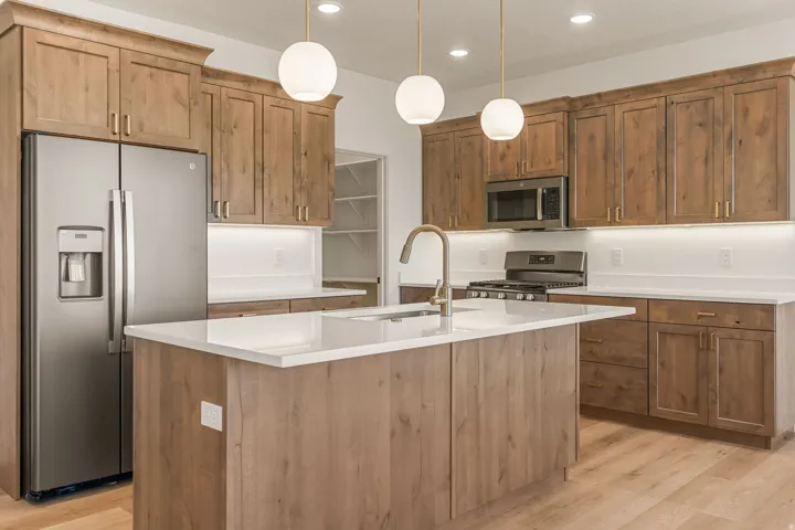Modern kitchen featuring wood-finish cabinetry, stainless steel appliances, and a central island with a white countertop