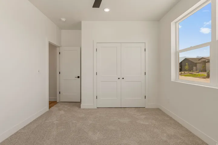 Room featuring neutral carpeting, a large window, white trim, and white walls