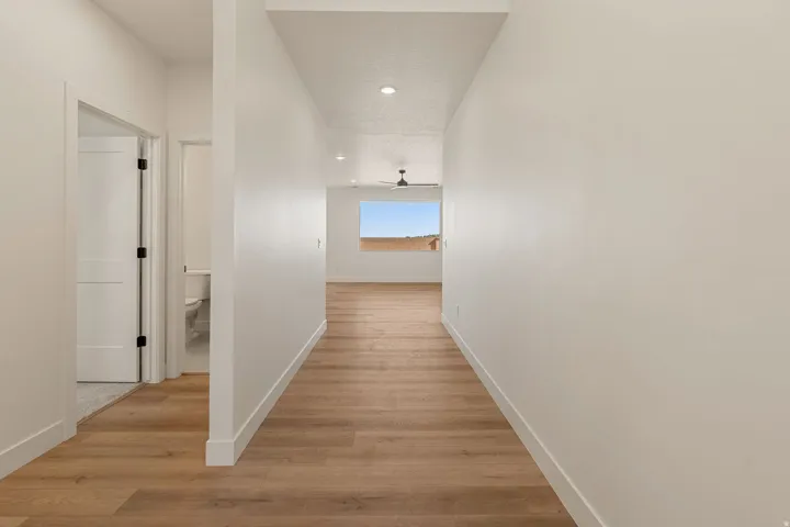 Hallway featuring wood-finish flooring extending into an open-concept area with a large window