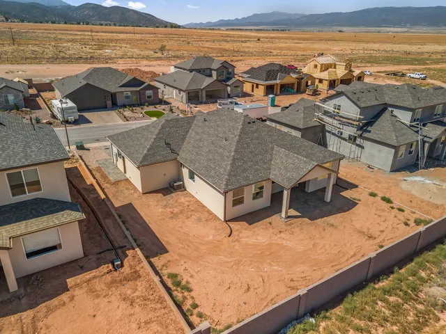 New construction residence featuring a covered patio, neutral stucco exterior, and a dark shingle roof