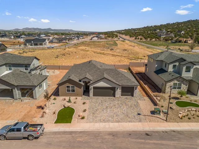 Single-story residence featuring a two-car garage, stone paver driveway, and a low-maintenance landscape design with artificial turf accents