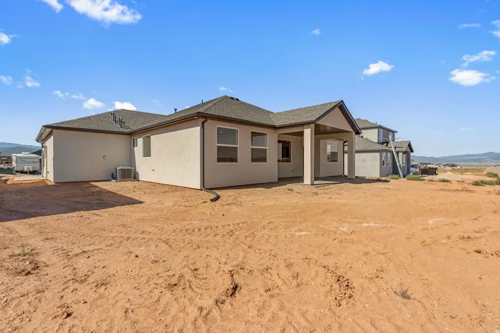 Newer construction home featuring a tan stucco exterior with a pitched roof and multiple gable details