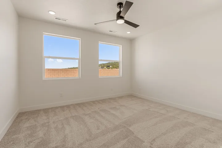 Spacious bedroom flooded with natural light through dual windows showcasing scenic landscape views