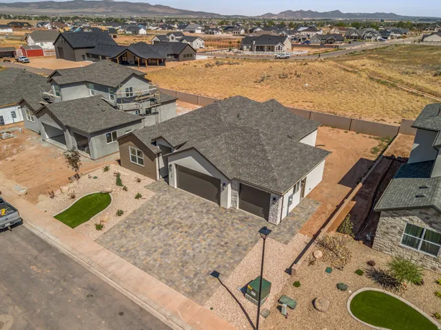 Contemporary residence featuring a paver driveway, an attached two-car garage, and a low-maintenance xeriscaped front yard with accenting green turf