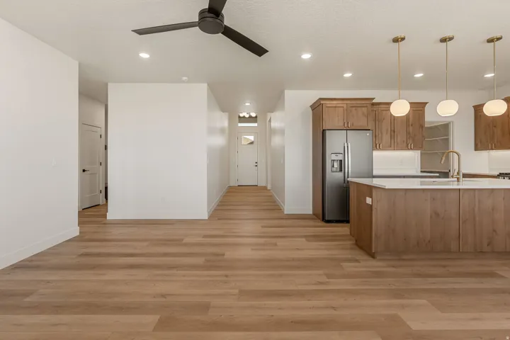 Spacious open-concept living area featuring wood-finish flooring, recessed lighting, and a modern ceiling fan