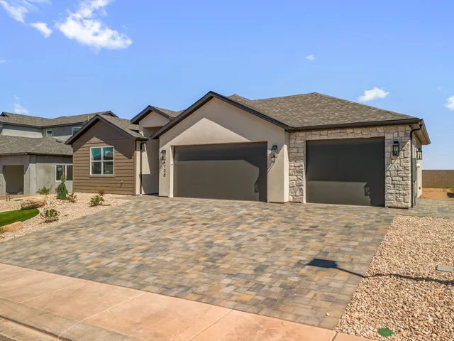 Modern two-car garage with dark-finish doors anchors this contemporary home, featuring a wide stamped concrete driveway with multi-tone paver pattern