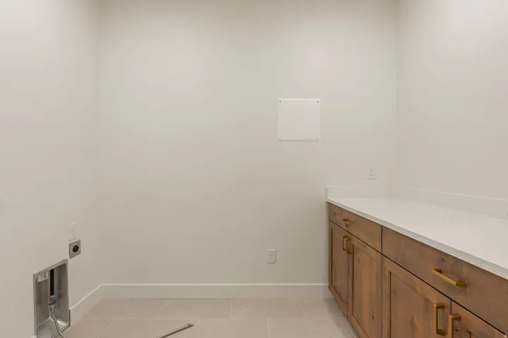 Laundry area featuring wood-finish cabinetry, light-toned countertops, and tile flooring