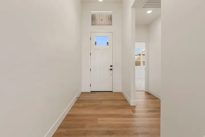 Entryway featuring a paneled door with glass inserts, transom window, recessed lighting, and wood-finish flooring