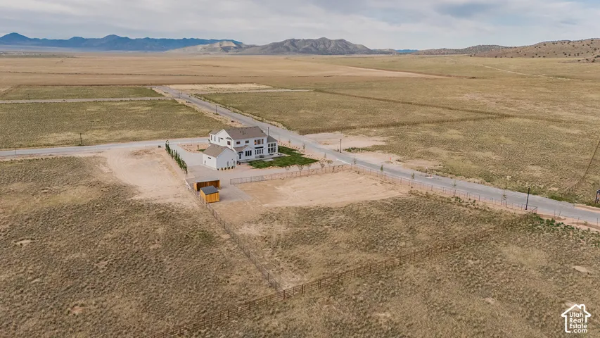 White two-story residence with attached garage, surrounded by expansive undeveloped land