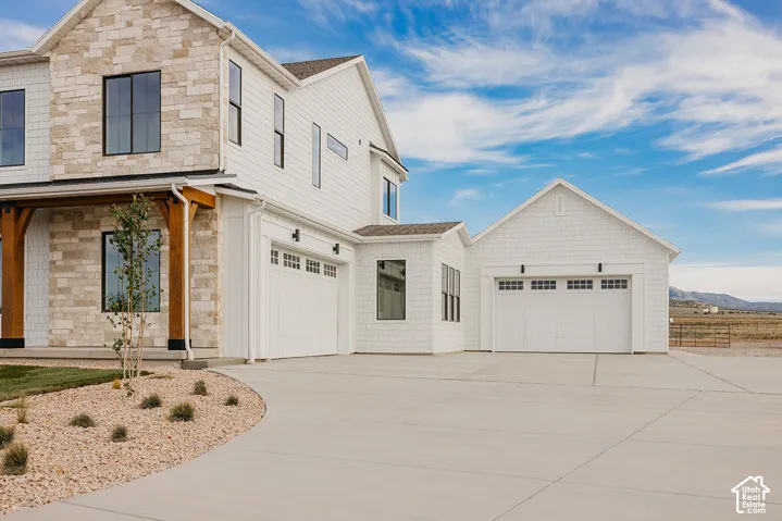 Stone veneer and white siding exterior with a multi-car garage