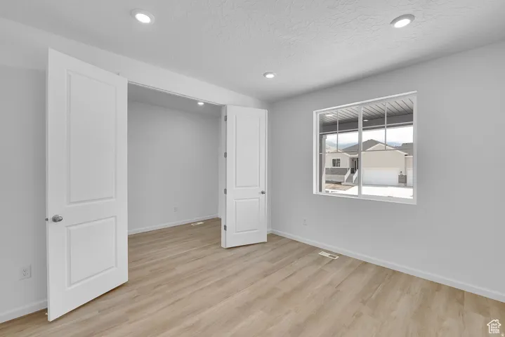 Room featuring wood-finish flooring, white walls, and recessed lighting