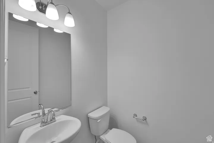Powder room featuring a pedestal sink with a chrome faucet, a rectangular mirror, and a three-light vanity fixture