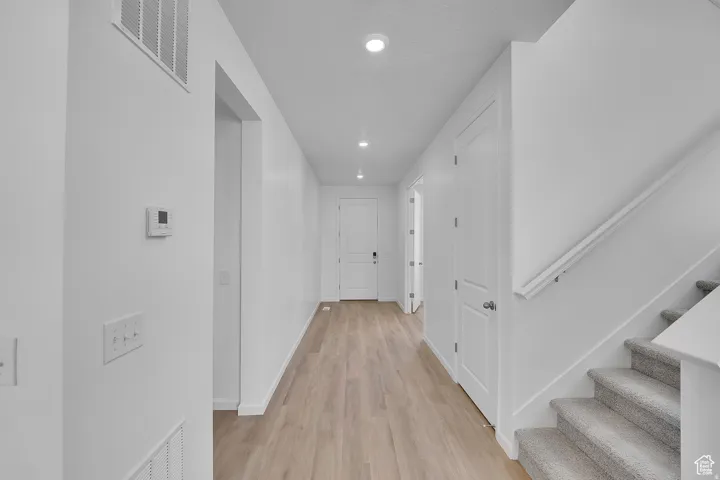 Bright hallway featuring light wood-finish flooring and recessed lighting