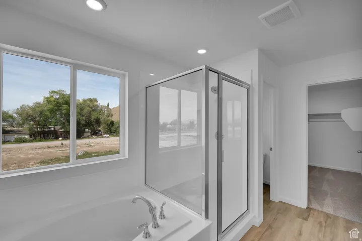 Spacious bathroom featuring a built-in tub with chrome fixtures, a clear glass shower enclosure, and recessed ceiling lighting