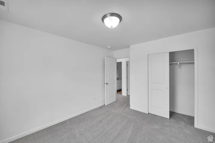 Neutral-toned room featuring carpet flooring, crisp white walls, and a ceiling-mounted light fixture
