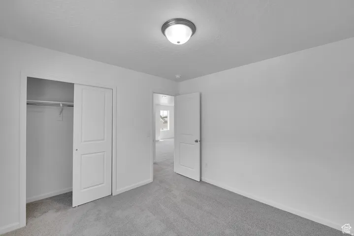 Carpeted room featuring a white interior door, a two-panel closet door, and a flush mount ceiling light