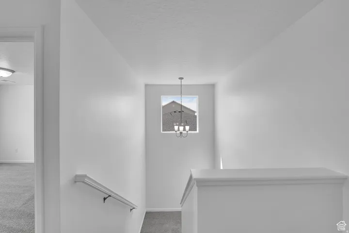 Upper-level landing featuring a contemporary chandelier, square window, painted banister, and coordinating handrail