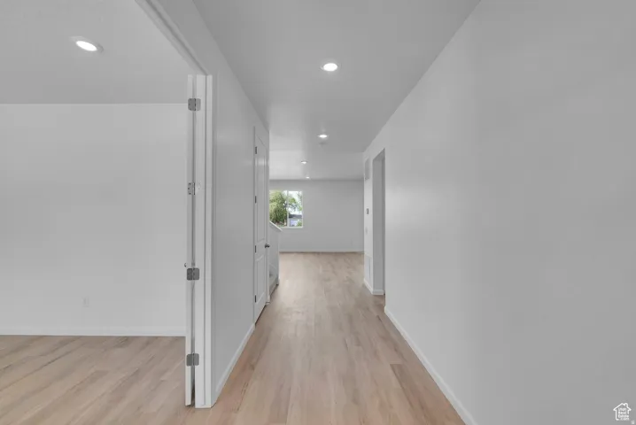 Hallway featuring recessed lighting, light wood-finish flooring, white walls, and bright white trim
