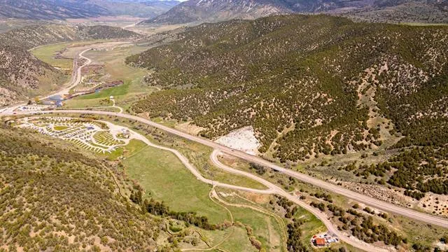 Expansive mountainous terrain with a winding highway and verdant valleys