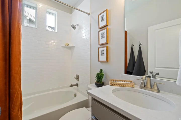 Bathroom featuring a tub/shower combination with subway tile surround and two transom windows