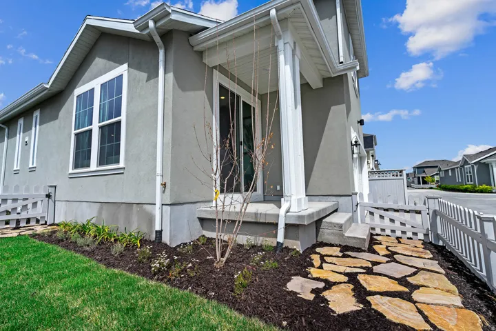 Stucco exterior featuring white trim windows and a covered patio with white columns