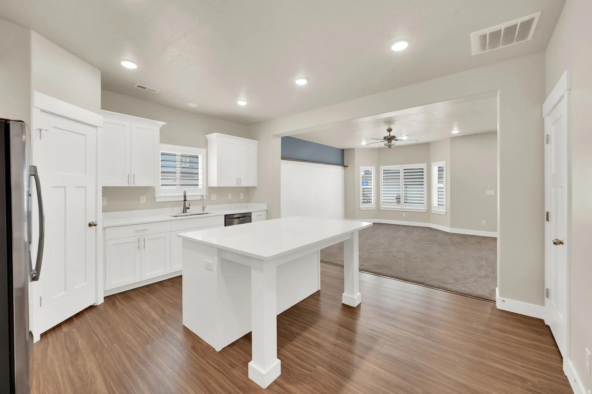 Open-concept kitchen featuring wood-finish flooring, recessed lighting, and white cabinetry