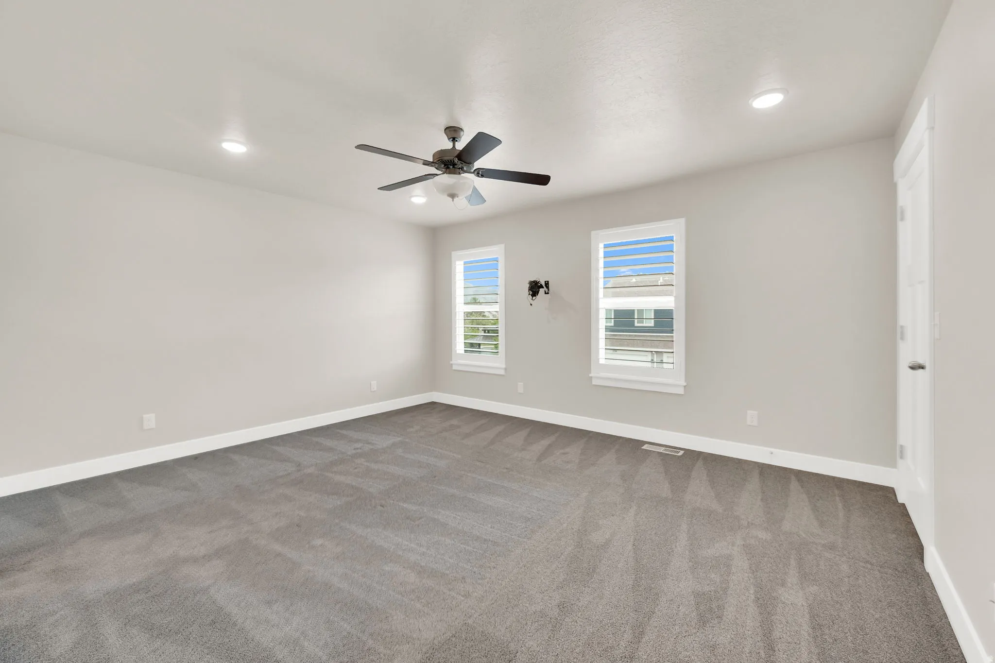 Spacious room featuring neutral carpeting, light-toned walls, and recessed lighting