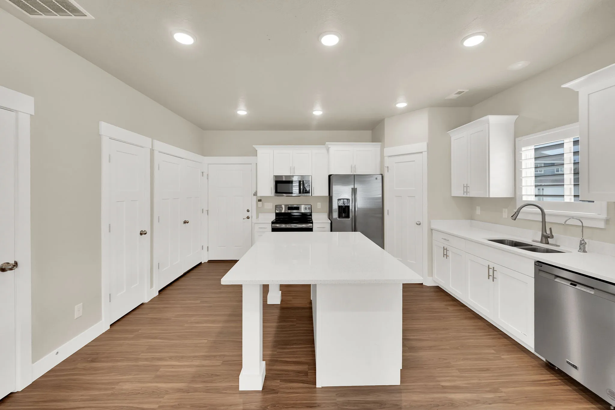 Open-concept kitchen featuring an expansive central island with a solid surface countertop