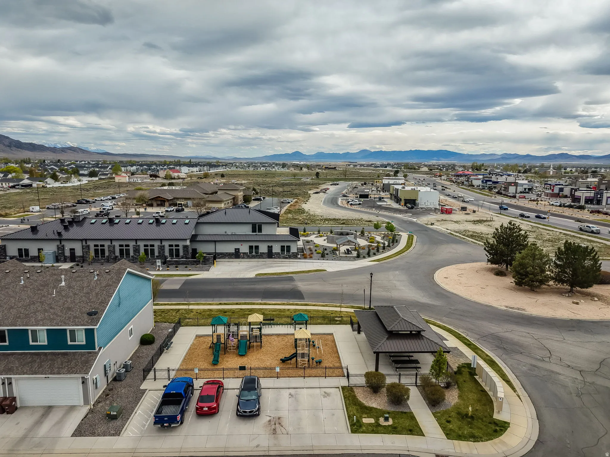 Community playground area featuring a play structure, a covered picnic area with seating, and adjacent residential structures