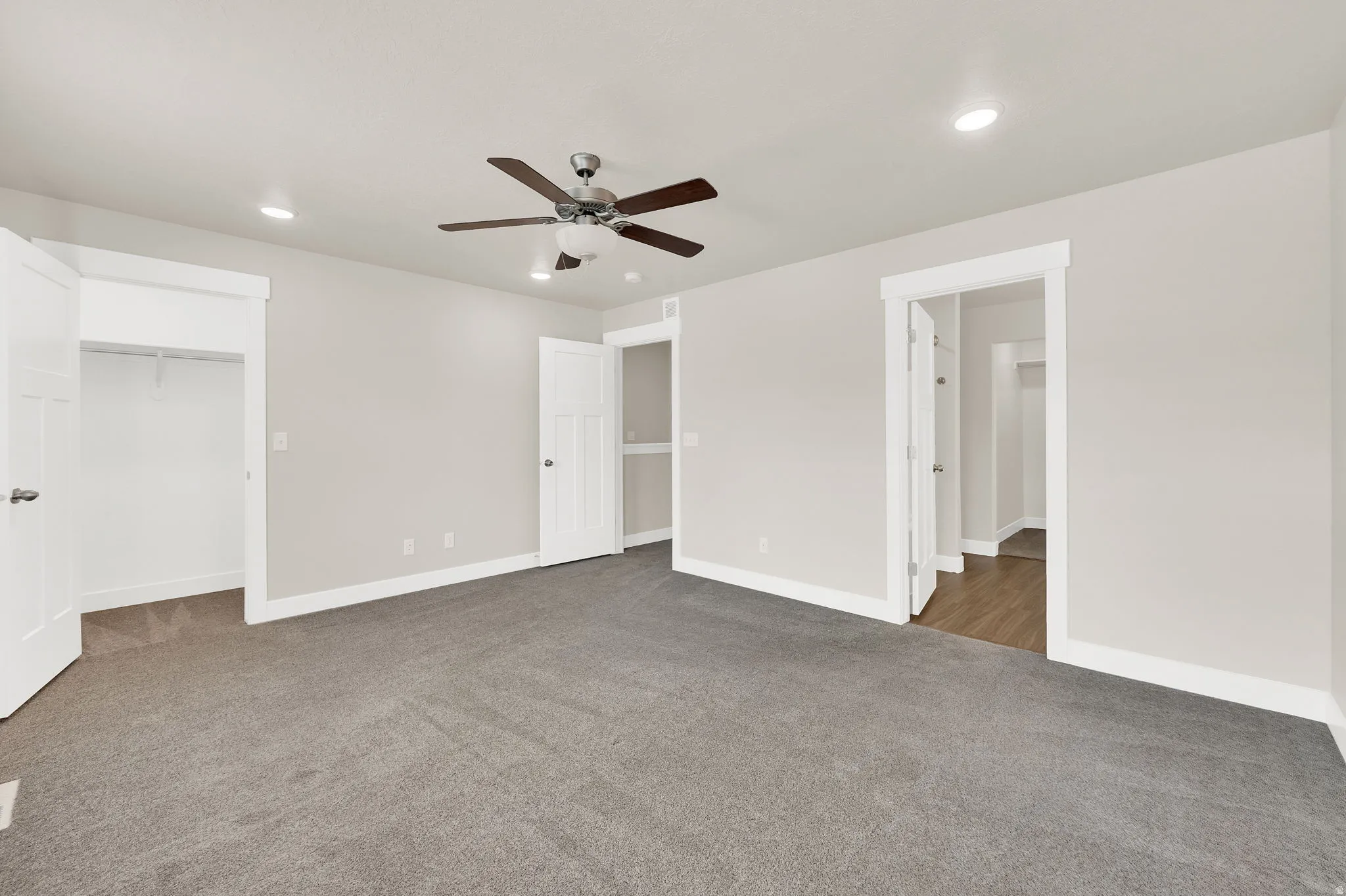 Spacious carpeted room featuring a ceiling fan with integrated lighting, recessed lighting, white baseboards, and white door frames