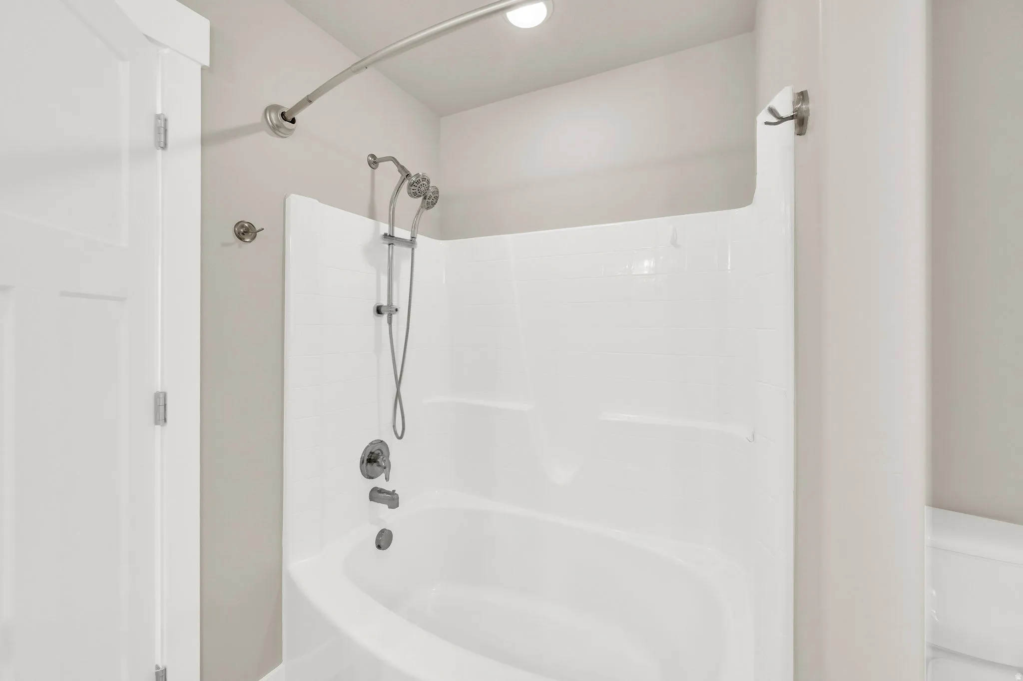 White acrylic tub and shower combination featuring a curved shower rod and brushed nickel fixtures