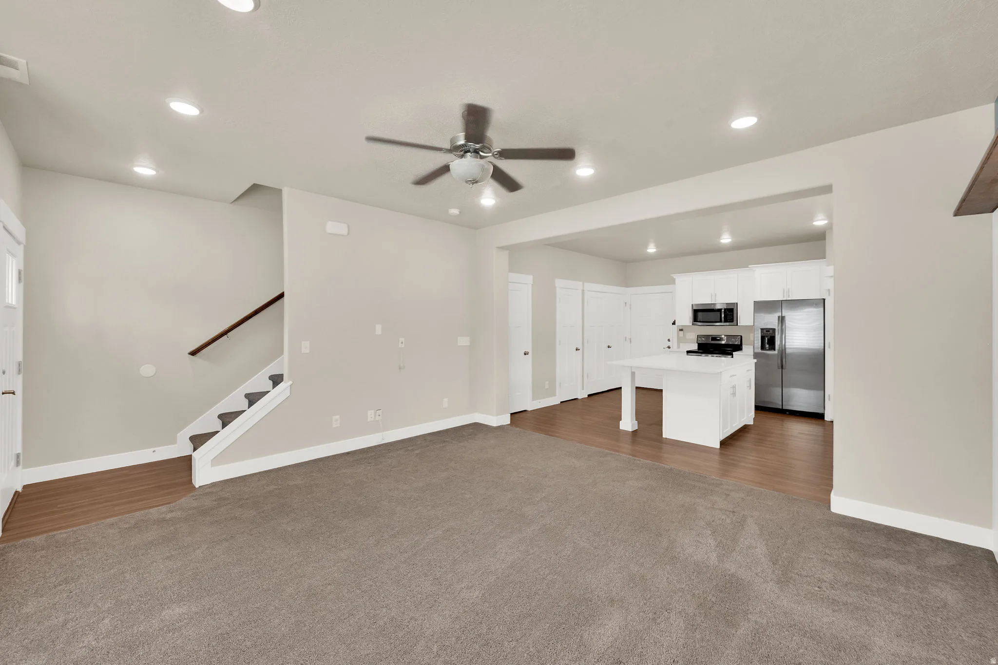 Open-concept living space featuring neutral paint, recessed lighting, and a ceiling fan