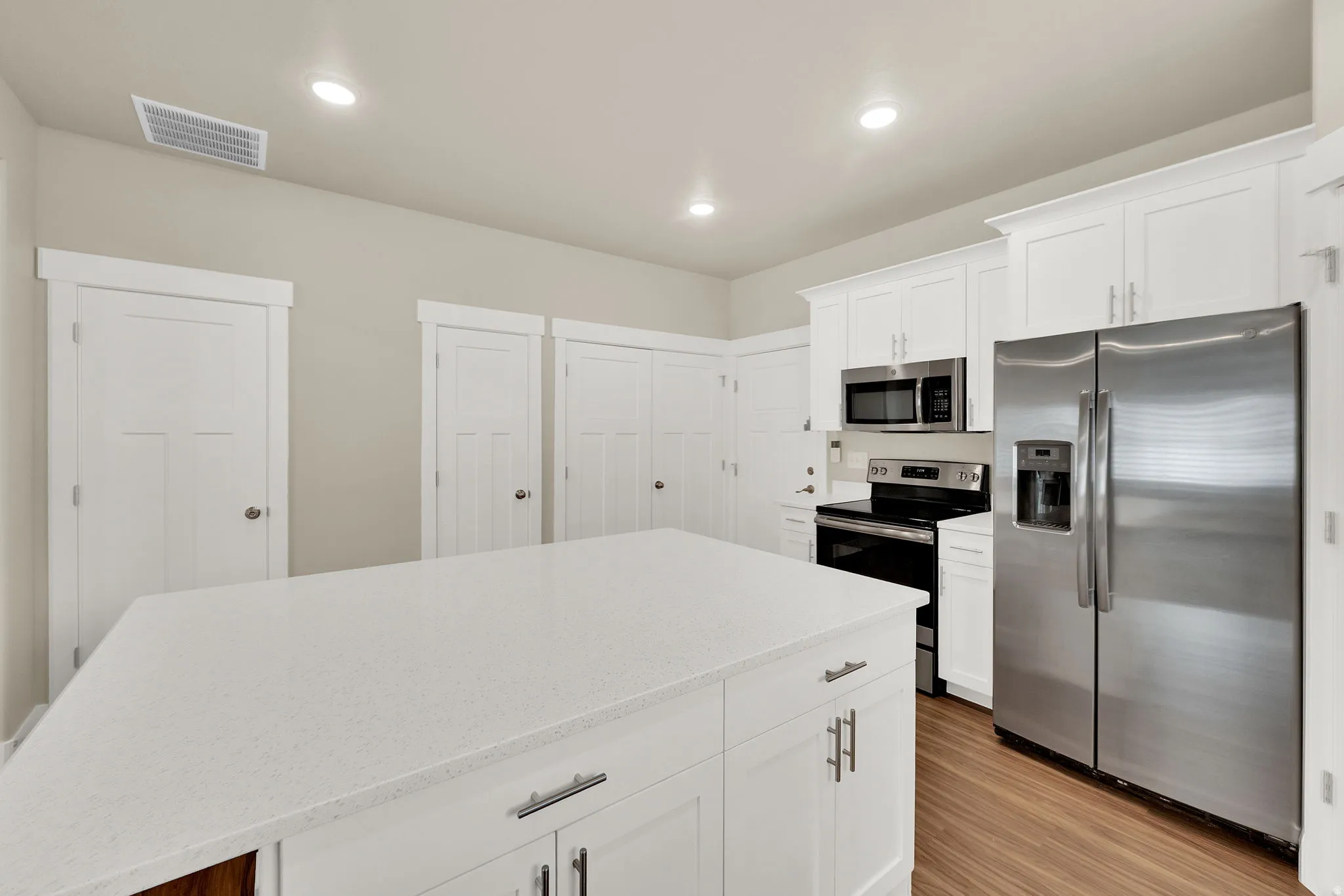 Kitchen island featuring a light-toned countertop with white cabinetry and chrome hardware