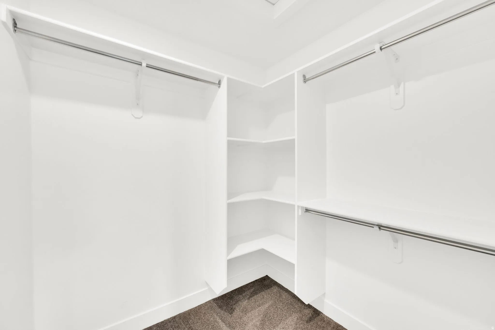 Walk-in closet with white shelving, integrated hanging rods, and corner shelving units