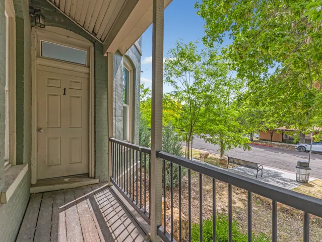 Unit 1 door with keypad entry and private balcony featuring wood-finish flooring and black metal railings.