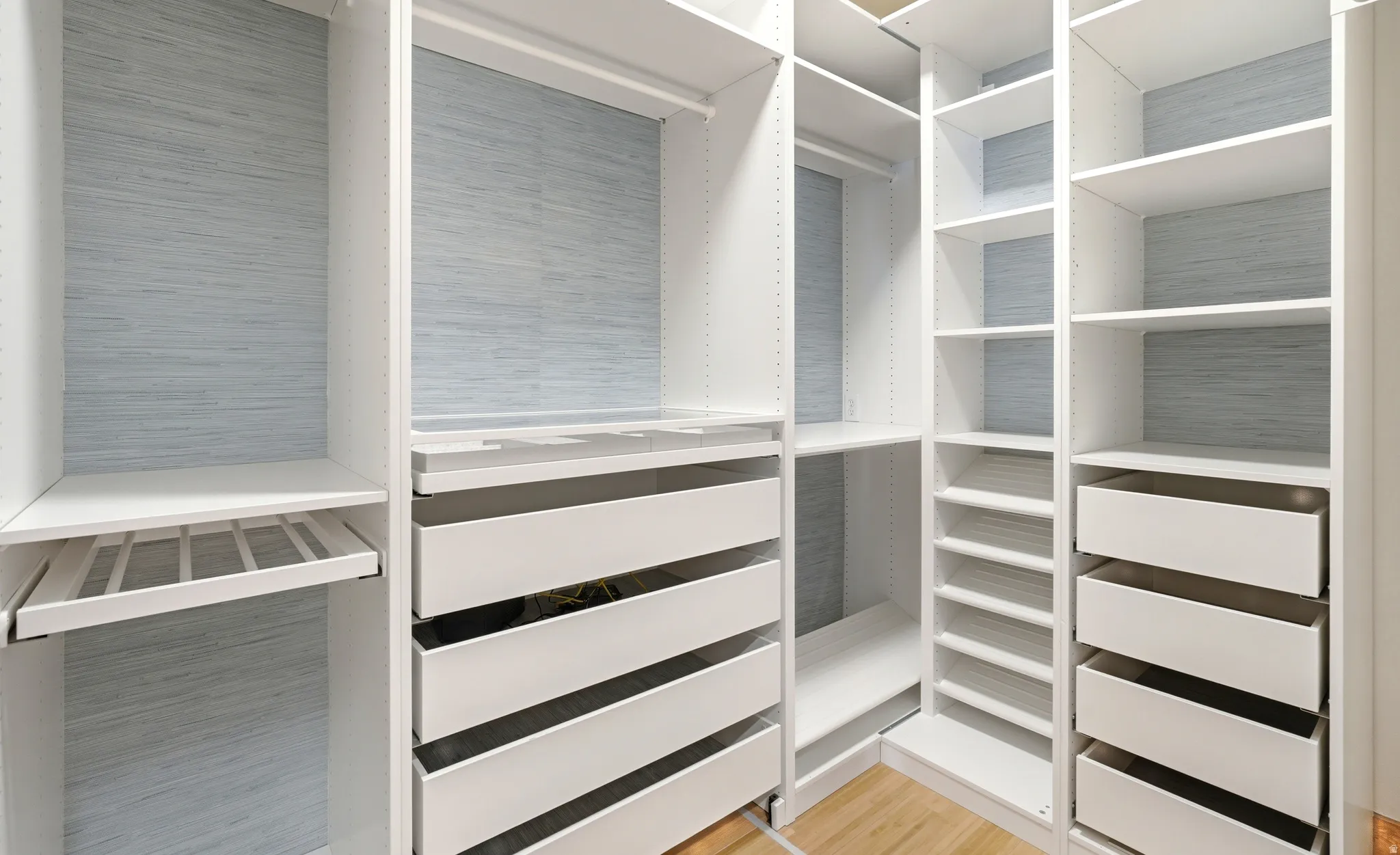 Custom closet system featuring pants hanger rack, shoe racks, jewelry drawer, valet hook, suitcase nook, and ironing board nook.