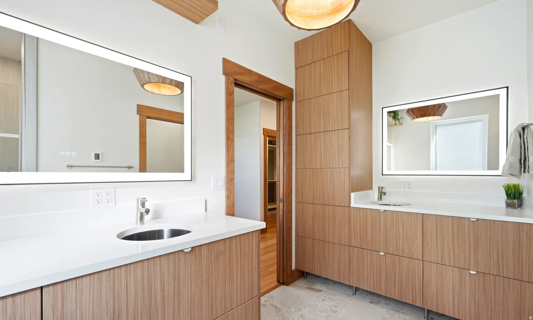 Dual vanity with integrated sinks, contemporary wood-finish cabinetry, quartz countertops, illuminated/heated mirrors, radiant floor heating and a dual shower head, walk-in tiled shower